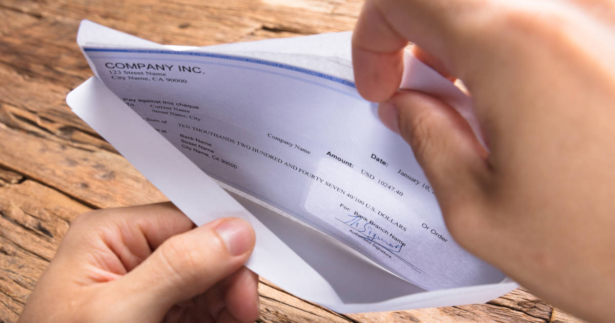 hands opening paycheck envelope